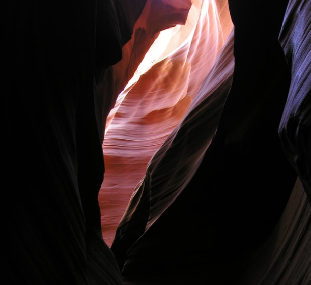 Antelope Canyon is a "slot" canyon located on Navajo land in Arizona. A slot canyon is like a cave, or tunnel, in that the opening at the top is very narrow, even closed in some spots. Sunlight filters in through slits in the roof, showing the rich colors and contours of the canyon walls.