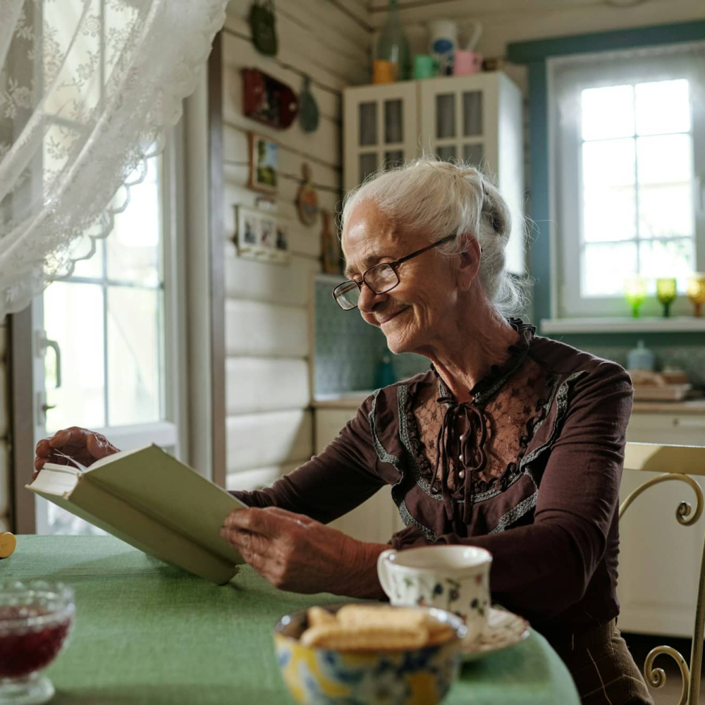 Happy aged woman in smart casualwear and eyeglasses reading book